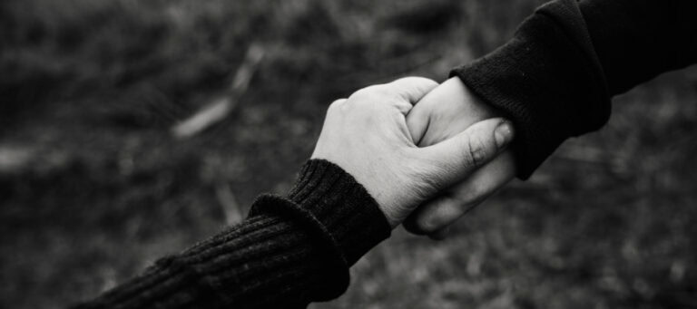 Two hands clasped together, symbolizing support and connection.