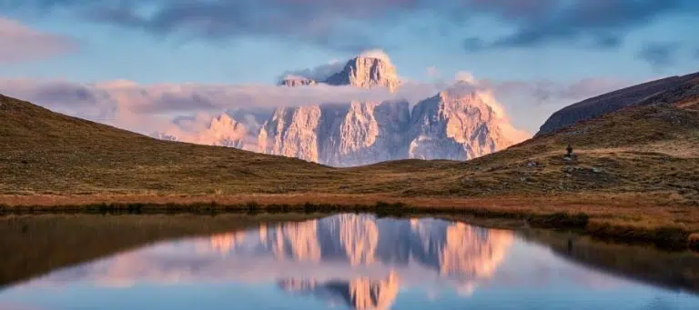 Serene mountain lake reflecting a majestic peak at sunrise.