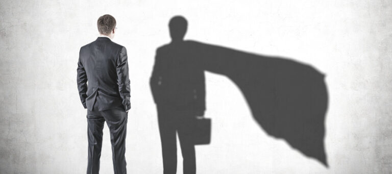 Businessman's shadow projects a superhero cape, symbolizing hidden potential and evolutionary psychology.