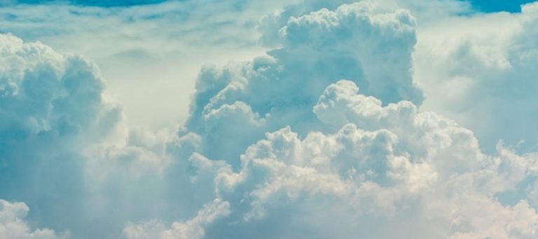 Fluffy white cumulus clouds fill a bright blue sky.
