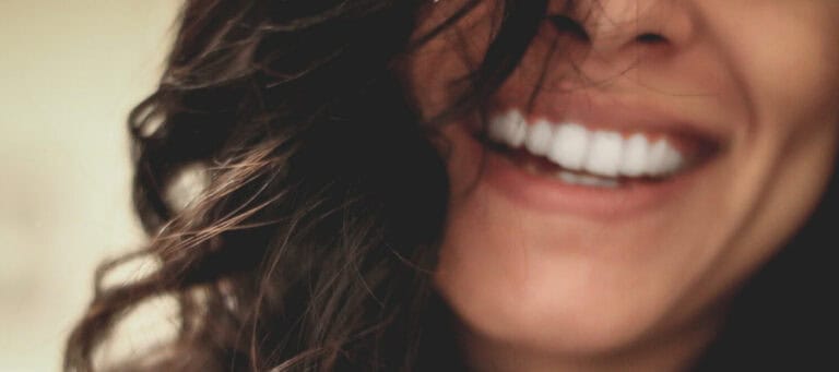 Close-up of a woman's smiling face, showcasing bright, healthy teeth.