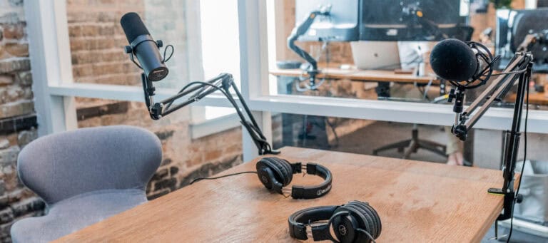 Podcast setup with two microphones, headphones, and a wooden desk.