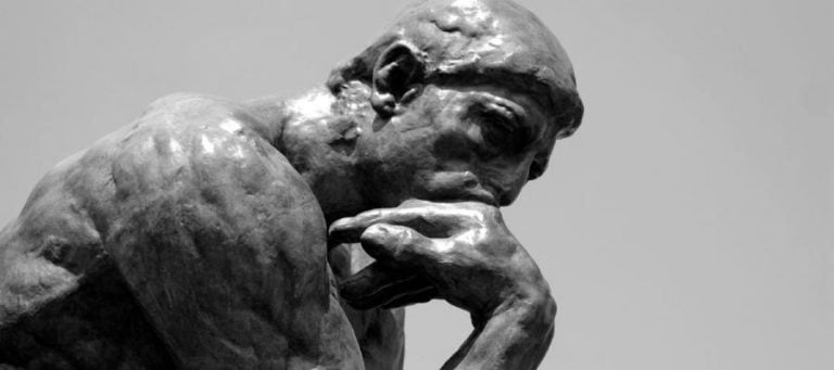 Black and white sculpture of a man in deep thought, reflecting on science, design, and faith.
