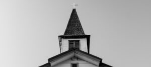Church steeple with cross against a clear sky.