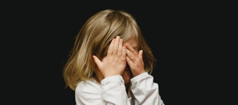 Young girl covering her eyes with her hands.
