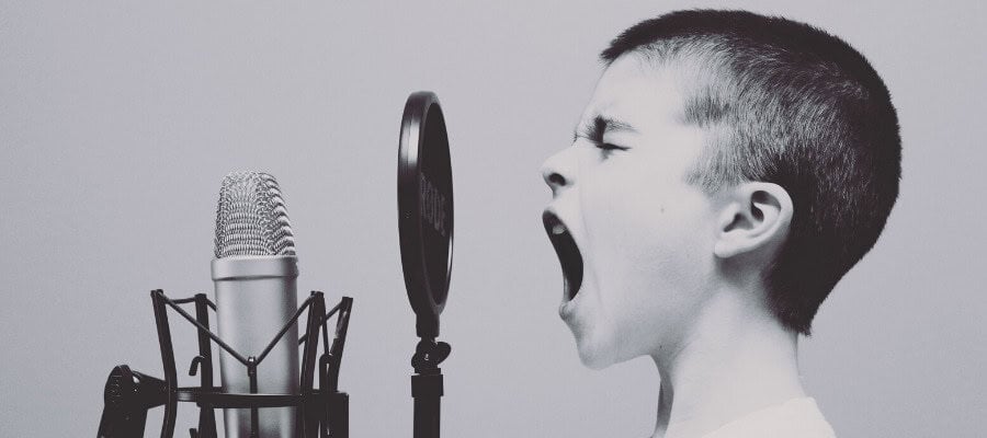 Boy yelling into microphone, expressing truth or falsehood.