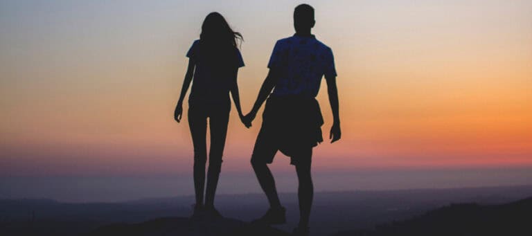 Silhouette of a couple holding hands at sunset.