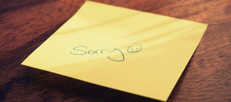 Yellow sticky note with handwritten "Sorry" and a smiley face.