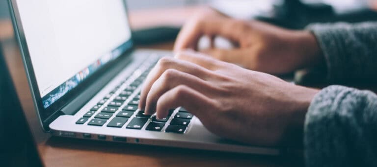 Person's hands typing on a laptop keyboard.