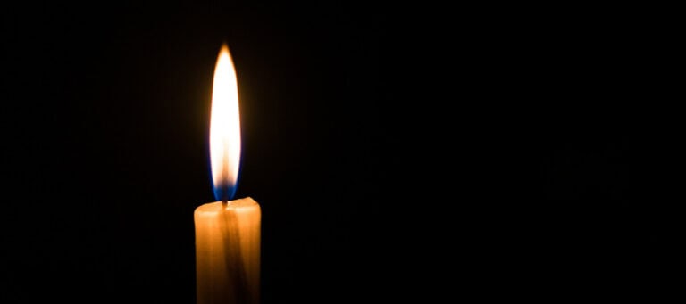 Single lit candle in the dark.