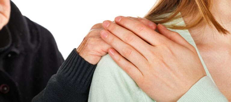 Older woman's hand gently resting on a young woman's shoulder; an example of altruistic behavior.