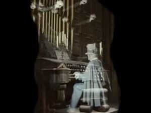 Ghostly organist plays a pipe organ in a dimly lit room, overcoming the terror of death.