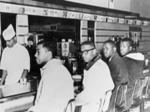 Four young Black men sit at a lunch counter, practicing civil disobedience.