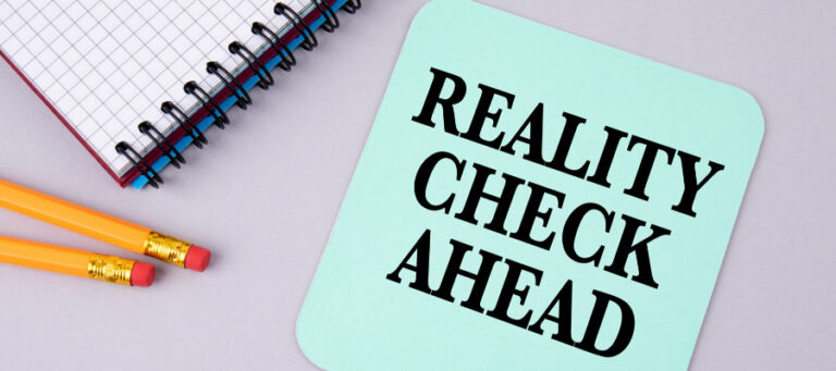 Notepad, pencils, and a teal card reading "Reality Check Ahead".