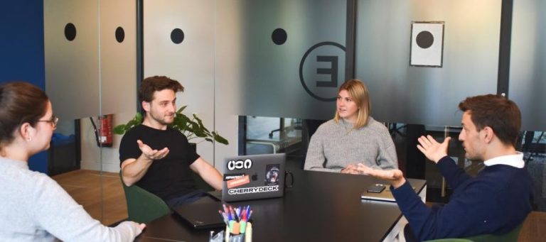 Four colleagues engaged in a business meeting, showing signs of disagreement.