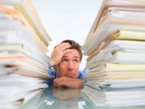 Frustrated businessman overwhelmed by stacks of paperwork. Too much information!