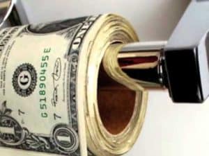 Roll of US dollar bills on a toilet paper holder; money and morality