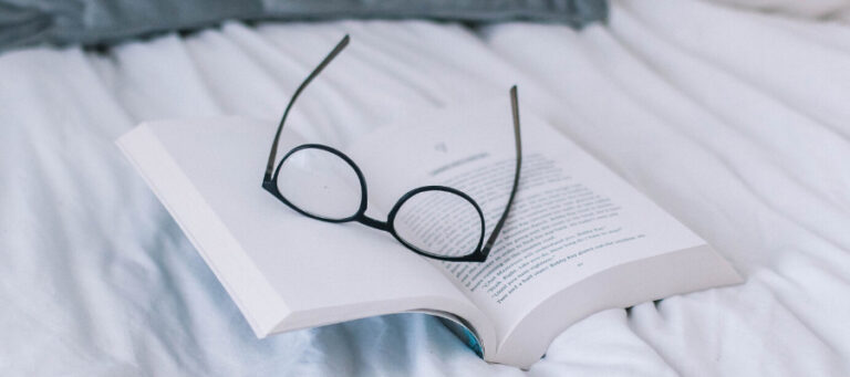 Open book with eyeglasses resting on it
