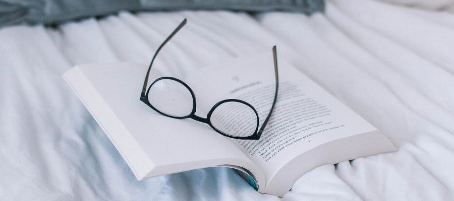 Open book with eyeglasses resting on it