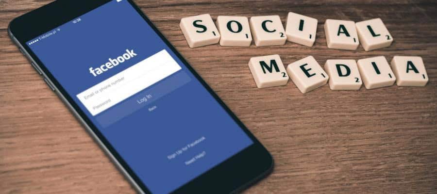 Smartphone displaying Facebook login screen; Scrabble tiles spell "Social Media