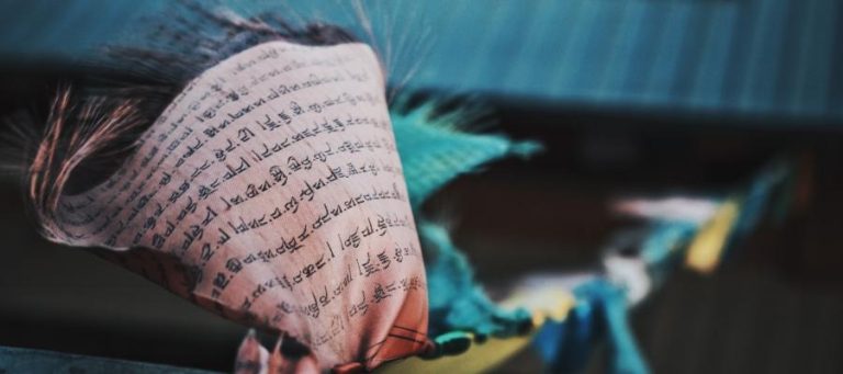 Close-up of prayer flags with Tibetan script, exploring themes of nihilism and meaning.