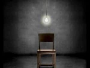 Empty chair in dimly lit room, single lightbulb overhead. Ethics of torture.
