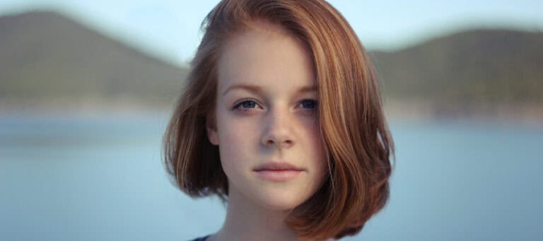 Thoughtful young woman looking at camera, contemplating environmental issues.