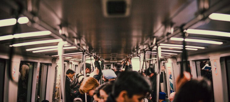 Crowded public transit car, passengers holding straps. Illustrates the impact of climate change on urban life.