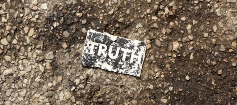Torn piece of paper on the ground reads "TRUTH".