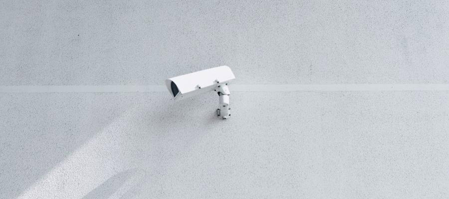 White security camera mounted on a light gray wall.