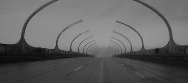 Empty highway with arched overhead structures creating a sense of enclosure.