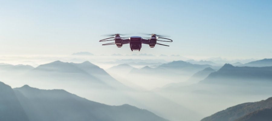 Drone flying over misty mountain range.