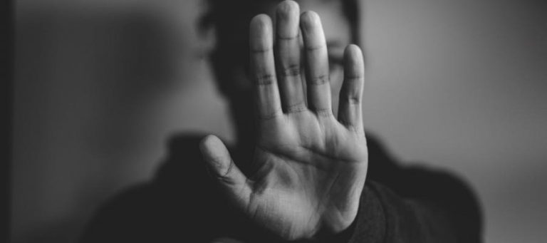 Person holding up hand, signifying stop or a need for personal space. Concept of safe space.
