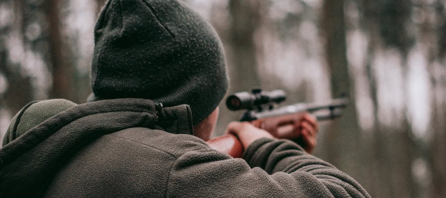 Hunter aiming rifle in forest
