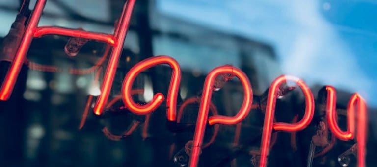 Neon sign reading "Happy" reflected in a window.