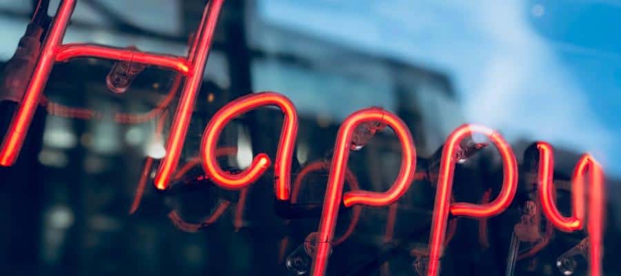 Neon sign reading "Happy" reflected in a window.