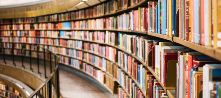 Curving library shelves overflowing with colorful books. Dewey Decimal System in action.