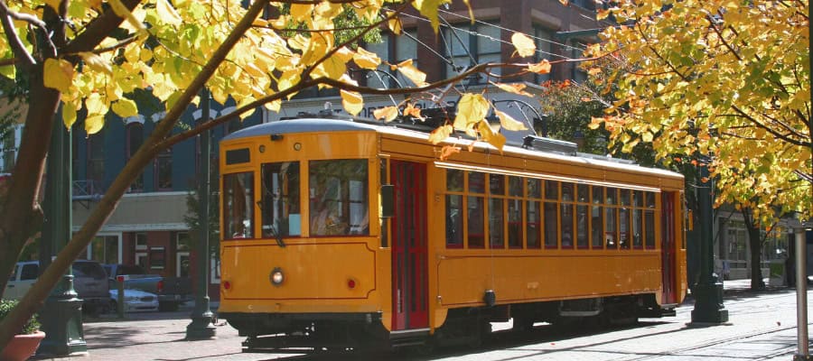 Vintage yellow streetcar on city street with autumn leaves