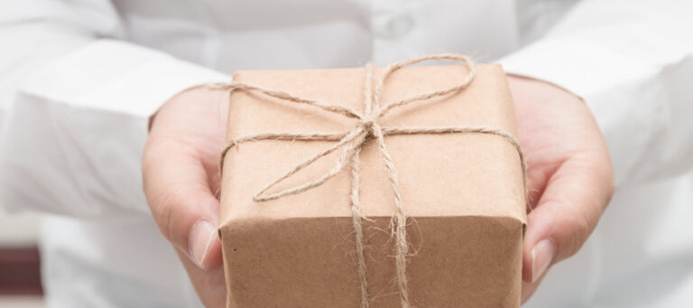Close-up of hands offering a small, wrapped gift.