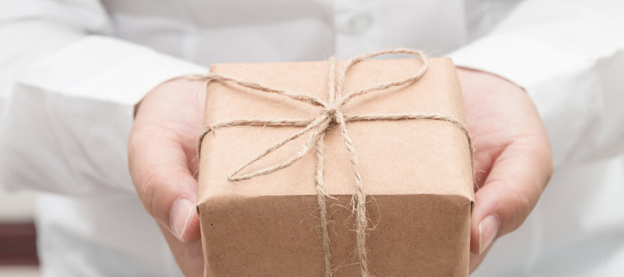 Close-up of hands offering a small, wrapped gift.