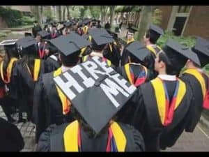 Graduates in caps and gowns, one cap says "Hire Me," illustrating the value of a college education.