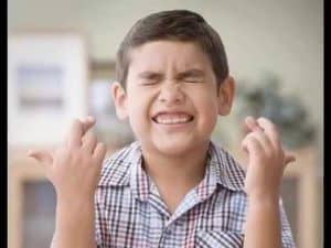 Boy with crossed fingers, exhibiting magical thinking.