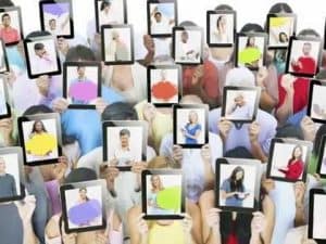 Diverse crowd holding tablets displaying self-portraits, exploring themes of self and self-presentation.