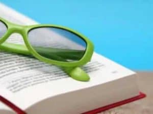 Lime green sunglasses rest on a book; summer reading.