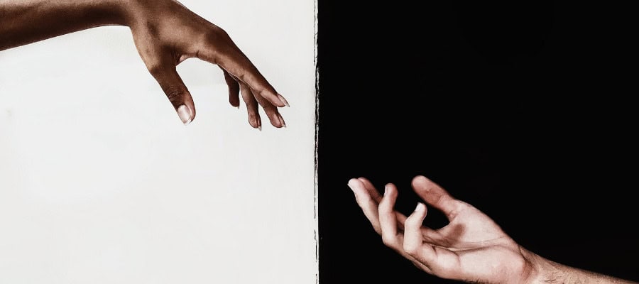 Two hands reaching across a black and white divide.