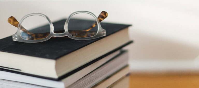 Eyeglasses resting on a stack of books.