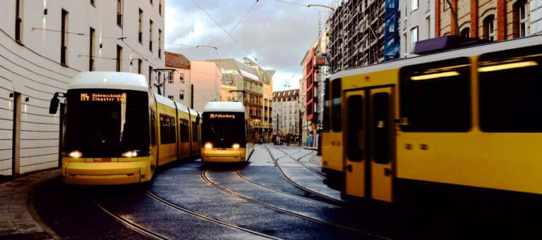 Three yellow trams on city tracks at dusk.