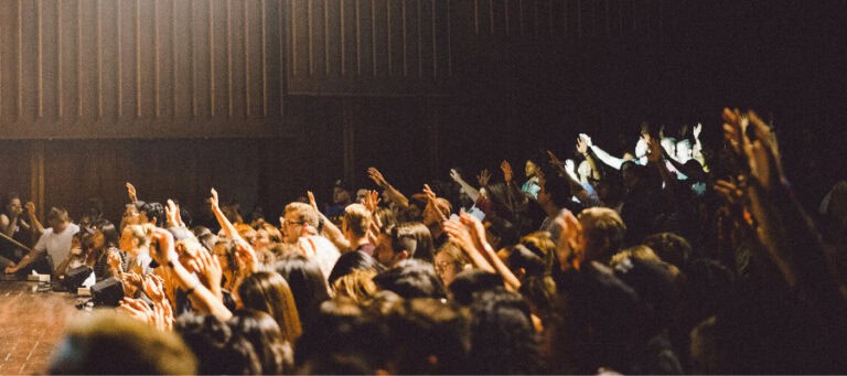 Large crowd of people with raised hands at a conference or event.