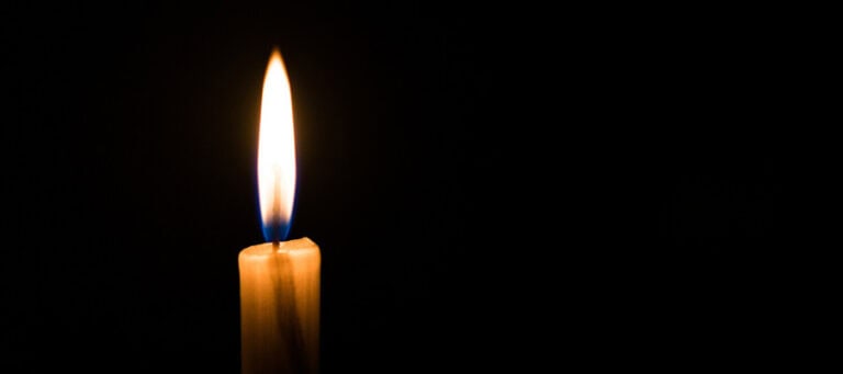 Single candle flame burning in the dark.