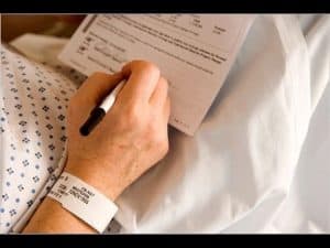 Close-up of a patient's hand signing a medical consent form.